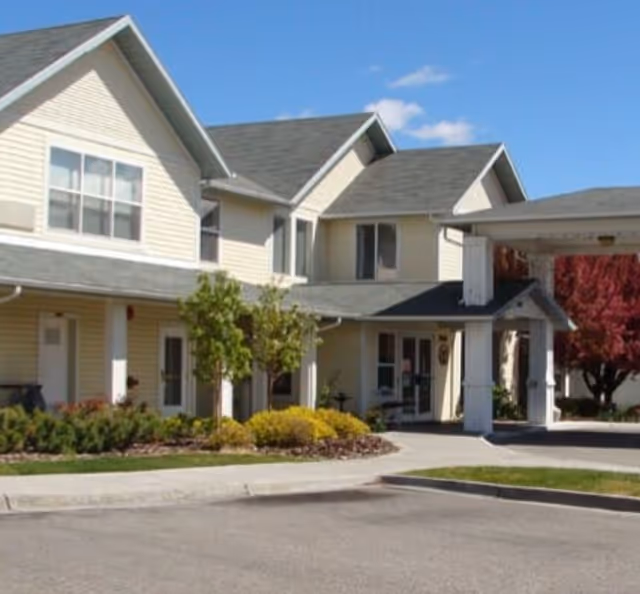 Exterior view of a beige senior living facility with landscaped front entrance
