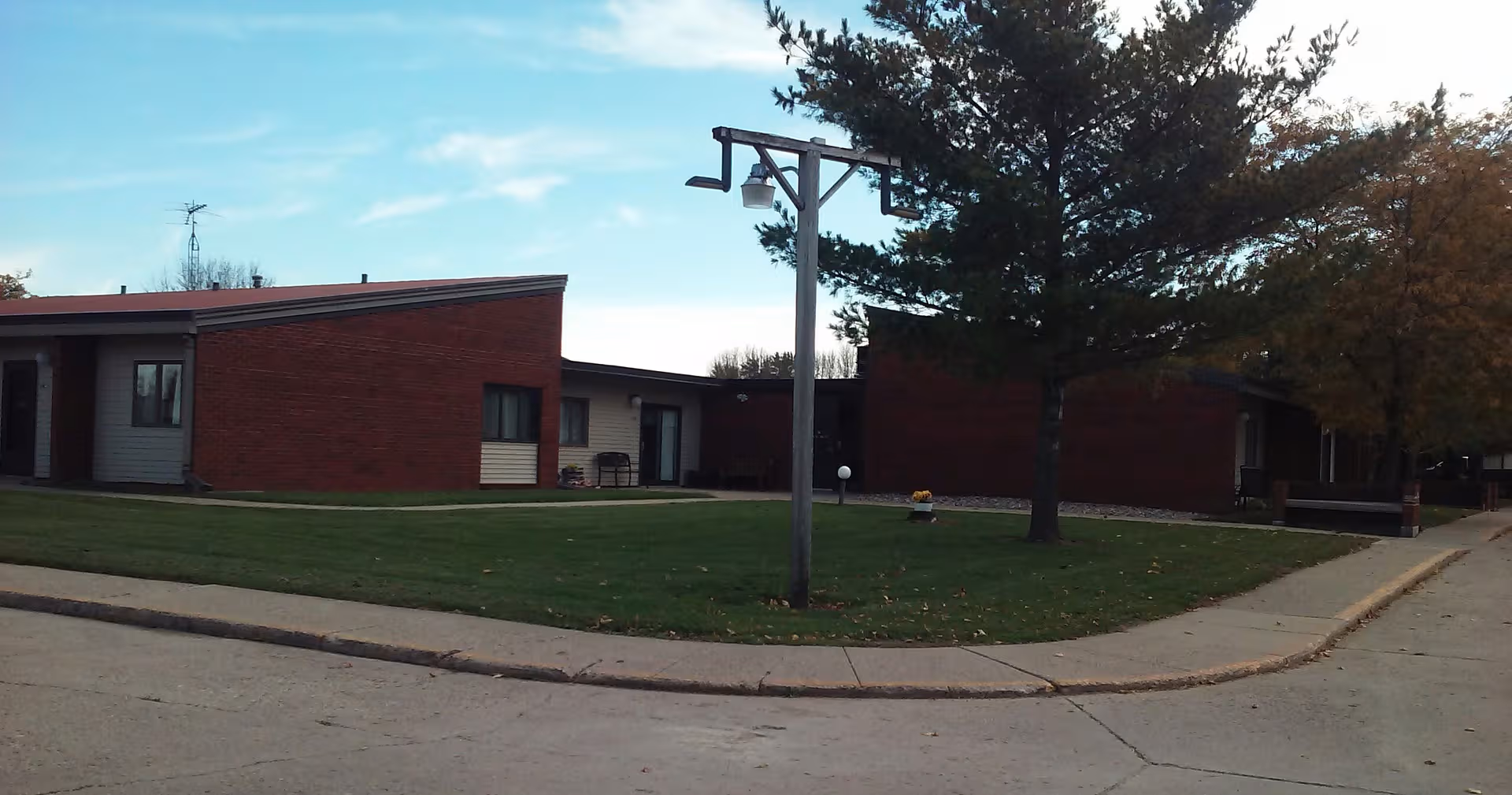 Exterior view of Westwood Knolls Retirement Center with brick building, lawn, and trees.