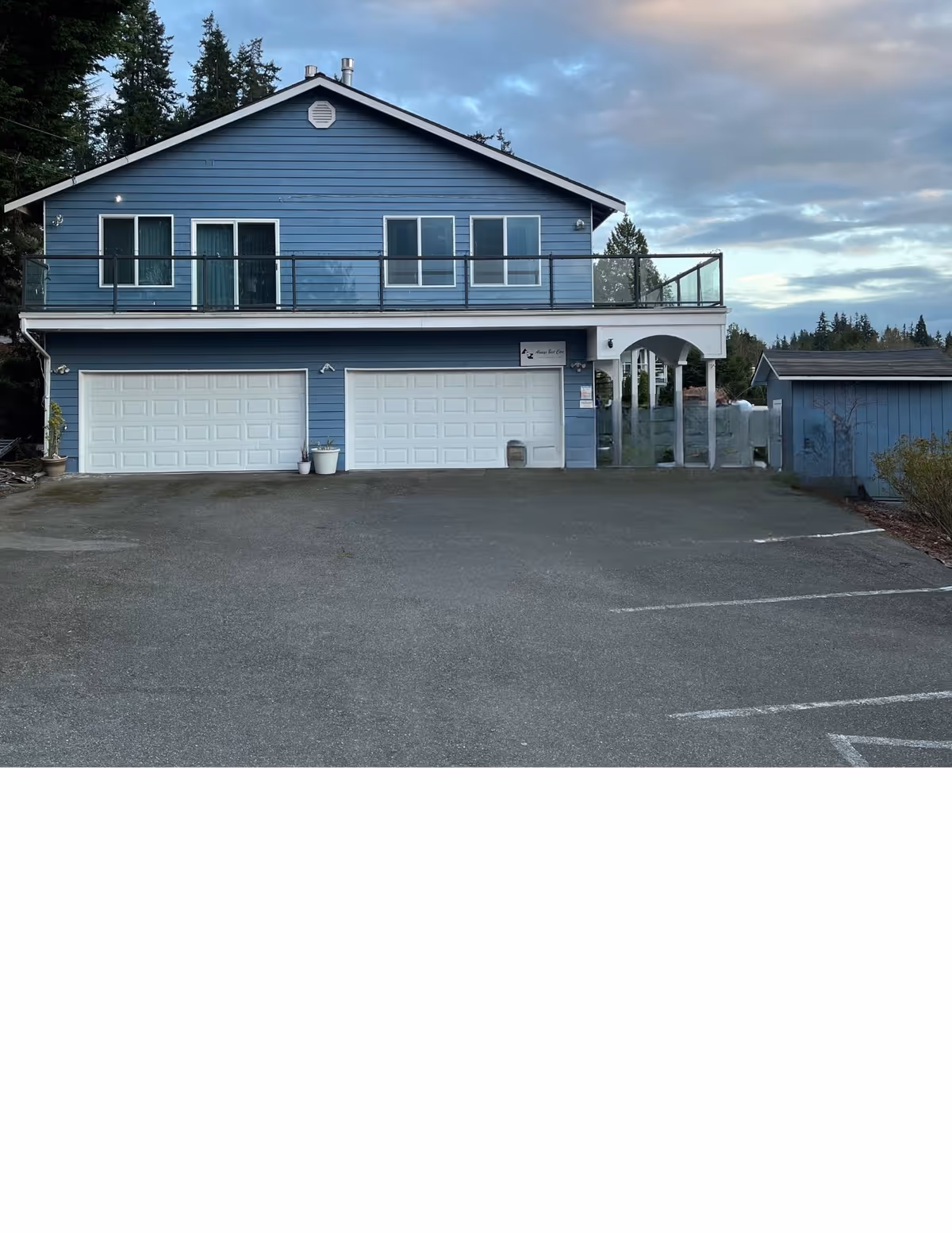 Blue two-story facility with a balcony and three garage doors, front exterior.