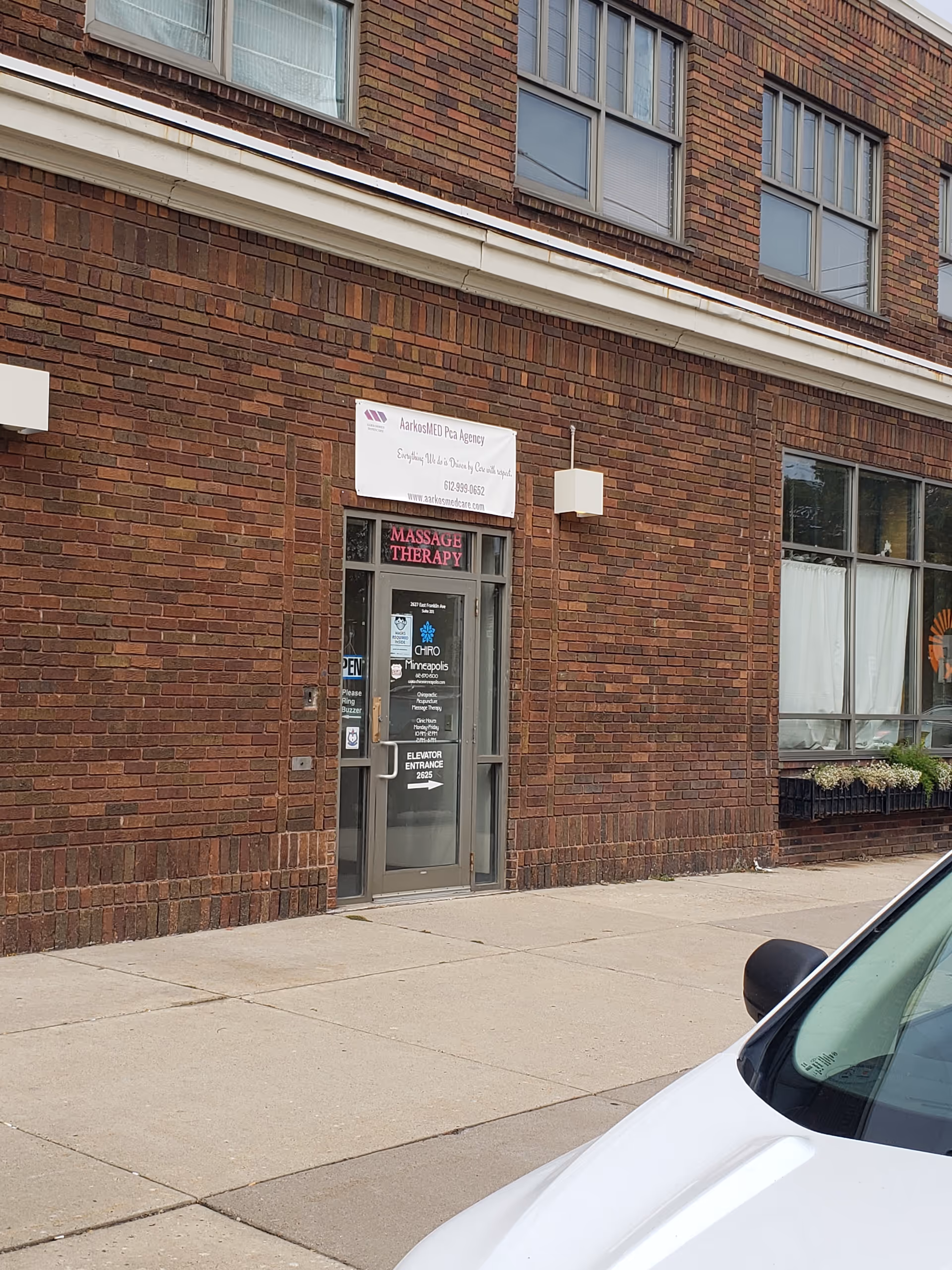 Brick storefront with AarkosMED signage and glass door entrance.