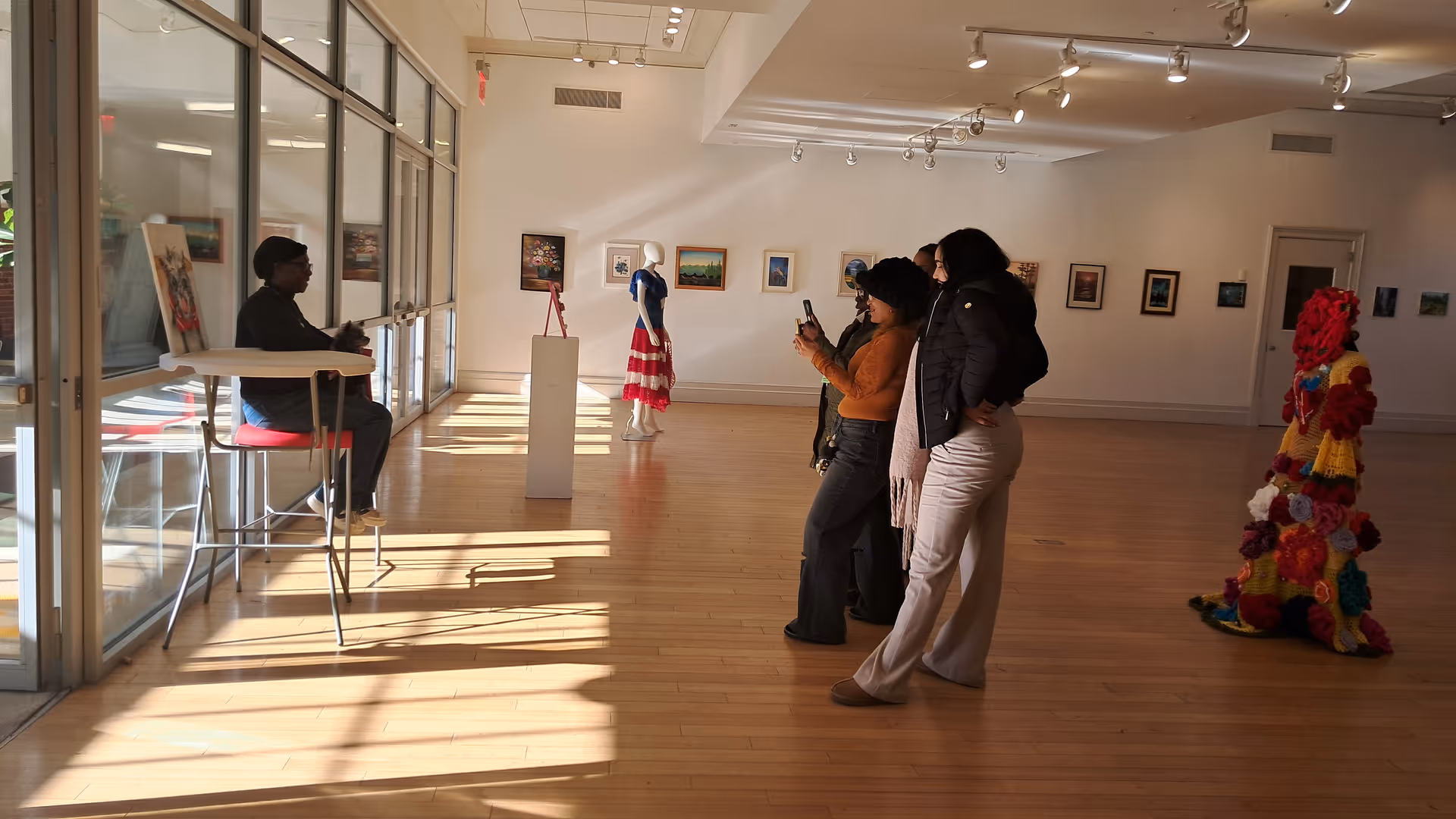 Residents and visitors view art in a bright gallery within a senior living facility.