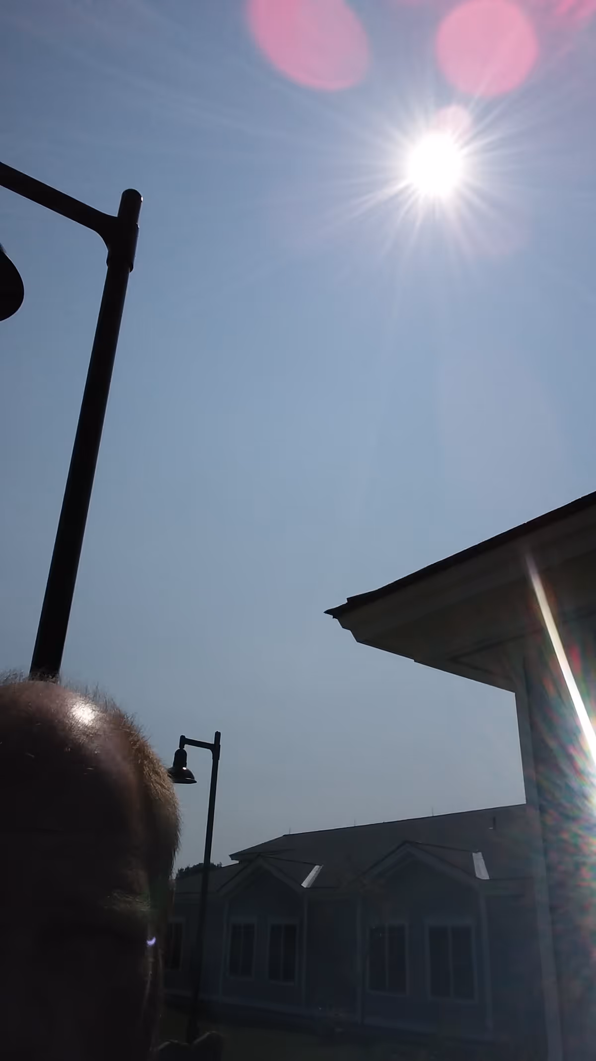 Bright sun over the exterior of a nursing home with street lamps.