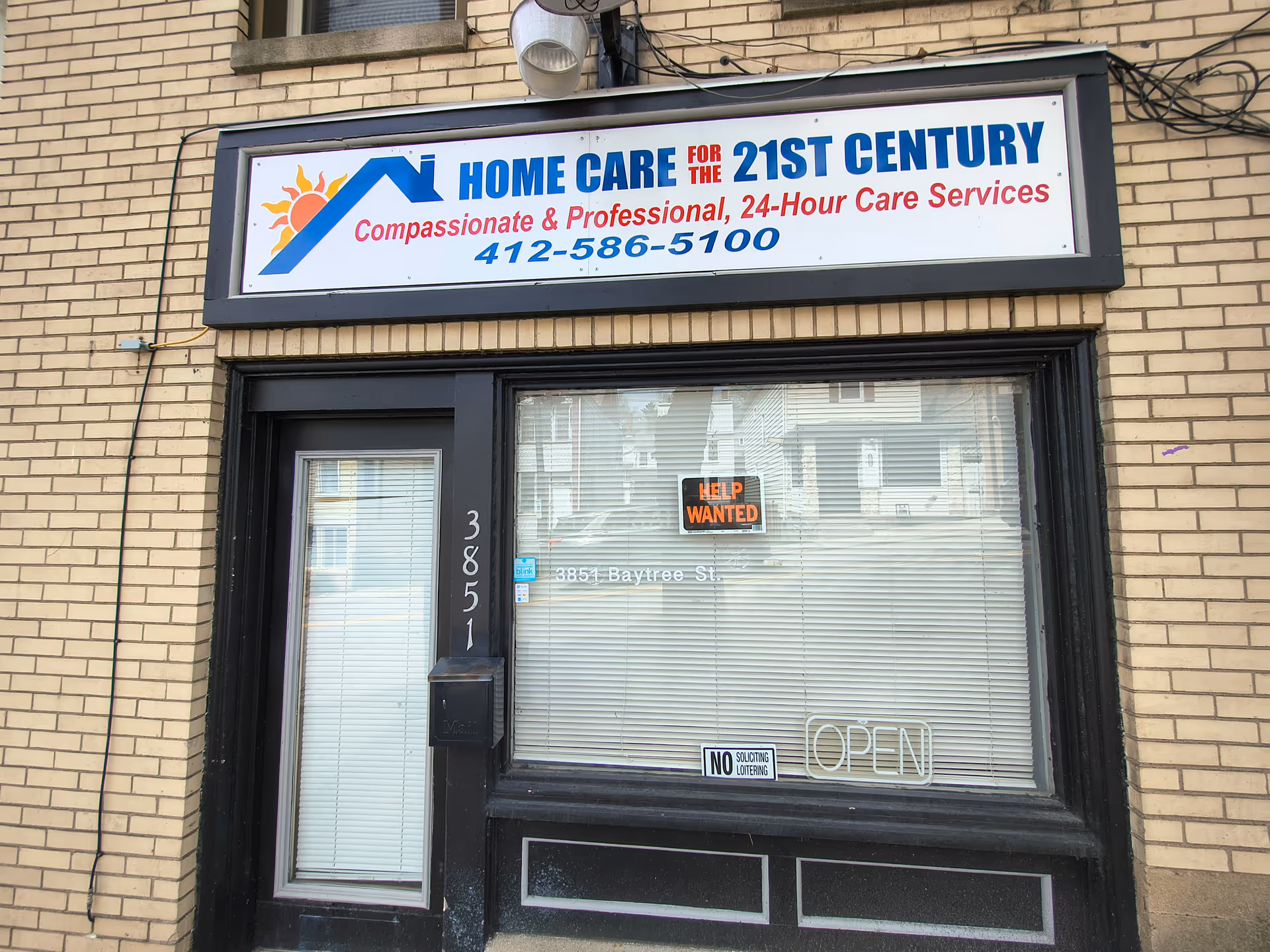 Brick storefront with a sign reading Home Care for the 21st Century above a glass door.