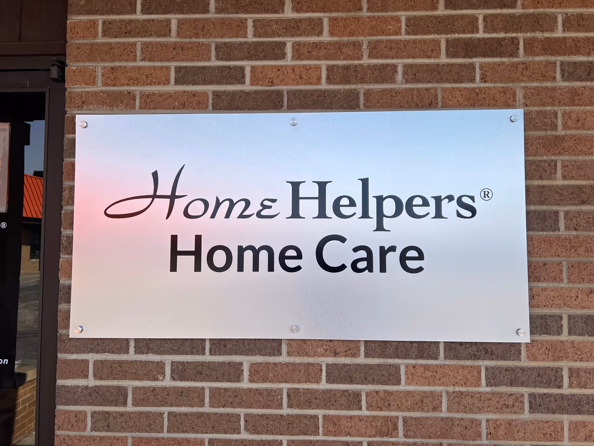 Metal sign reading Home Helpers Home Care on a brick exterior wall.