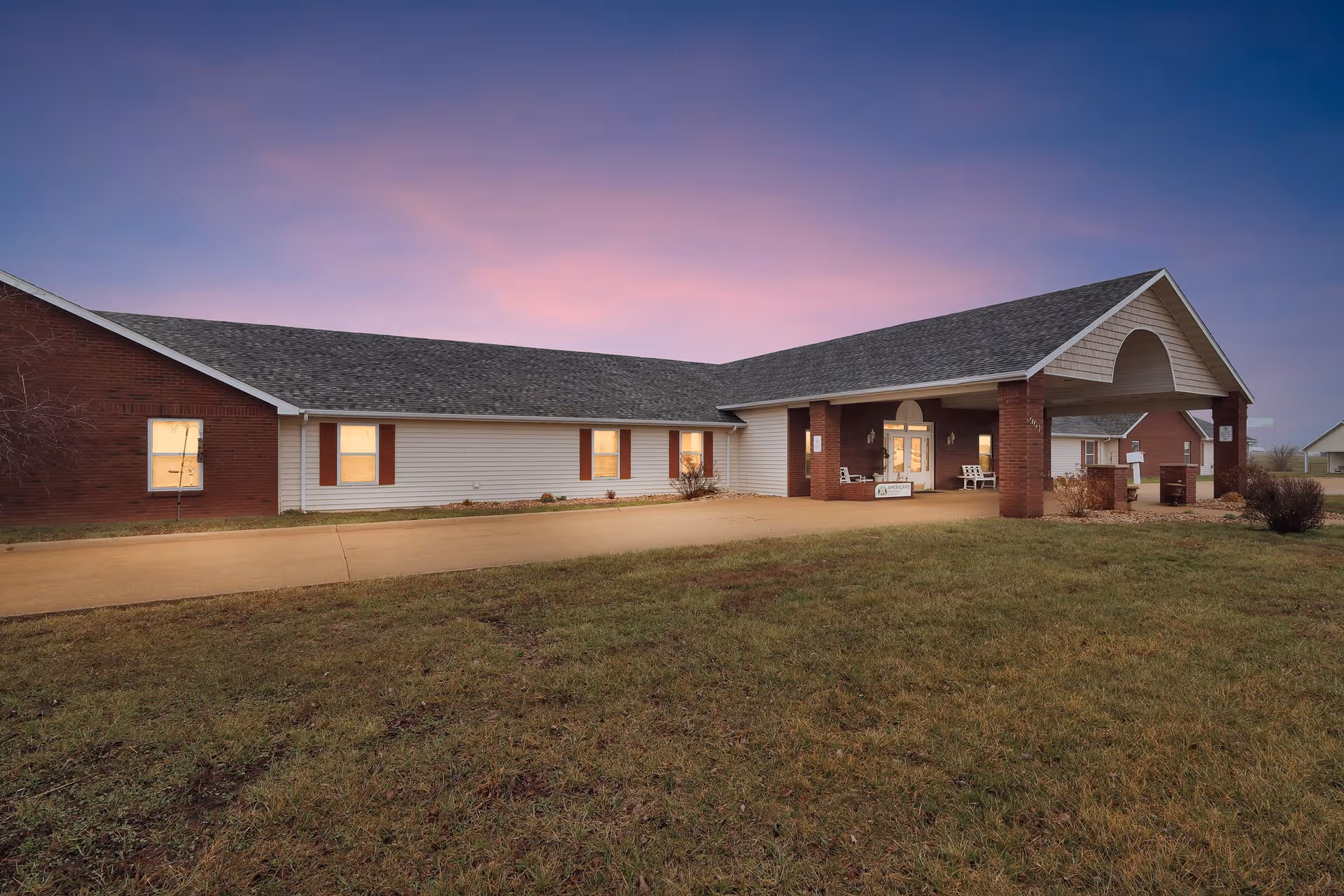 Single-story senior living facility with brick accents and a covered front entrance at dusk