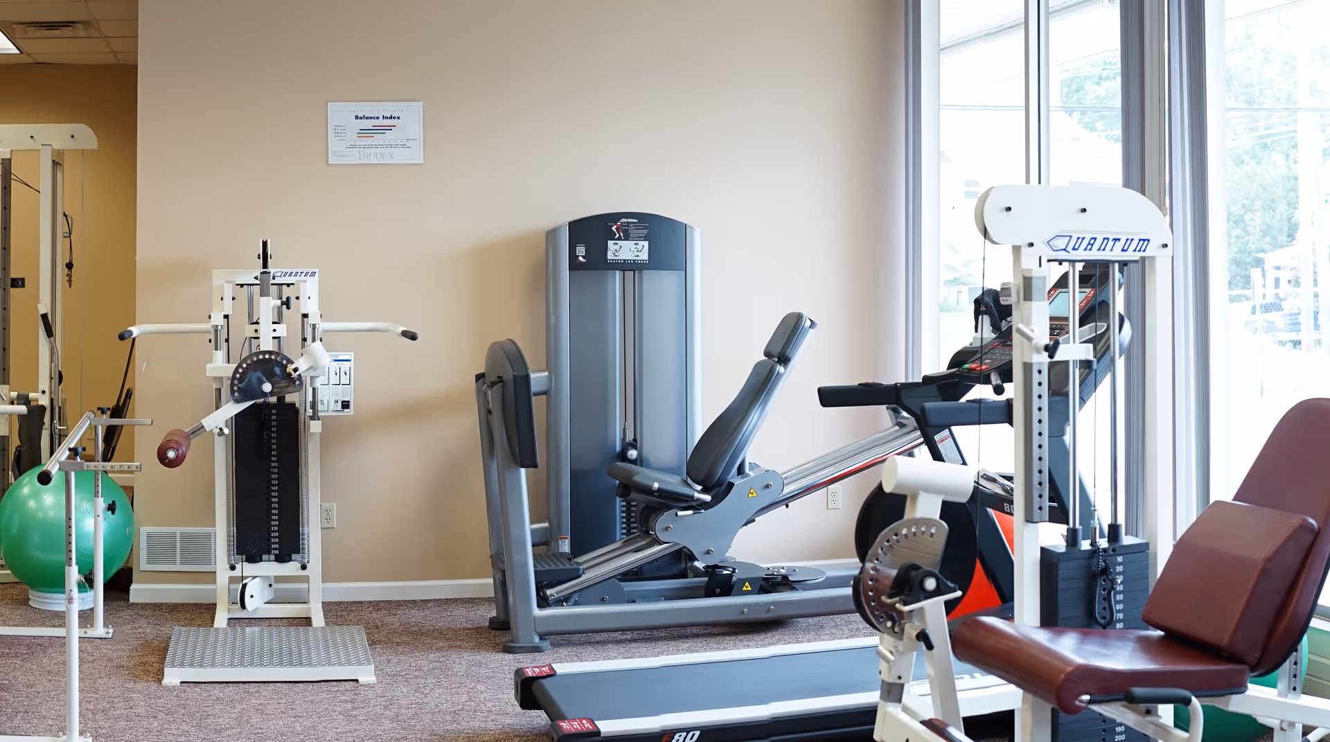 Interior gym room with cardio machines, weight bench, and therapy equipment.
