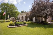 Front view of Life Care Center of Rochester with a manicured lawn and flag.