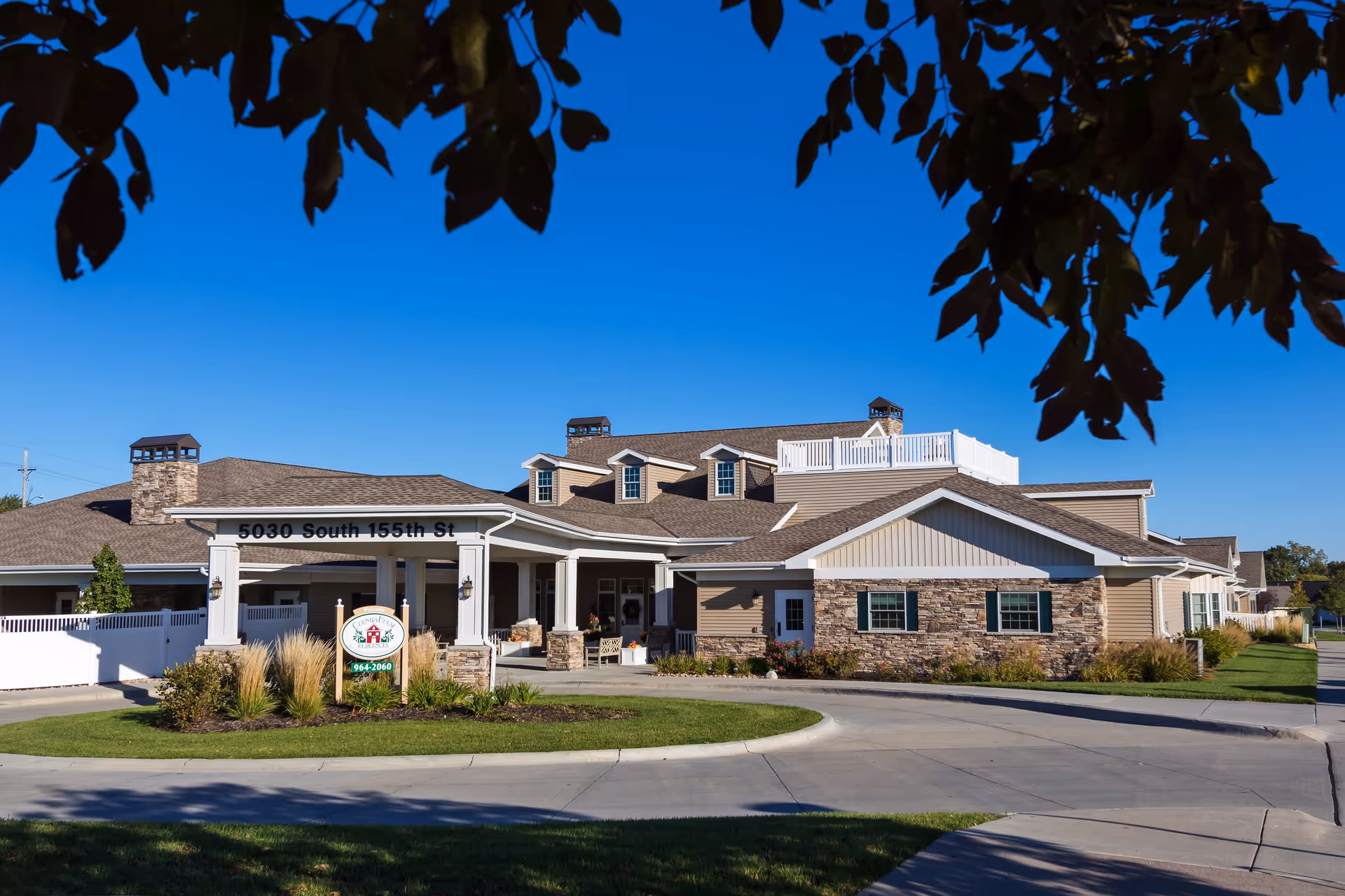 Front exterior of CountryHouse Residence senior living building with a covered portico, stone accents, and a landscaped circular driveway.