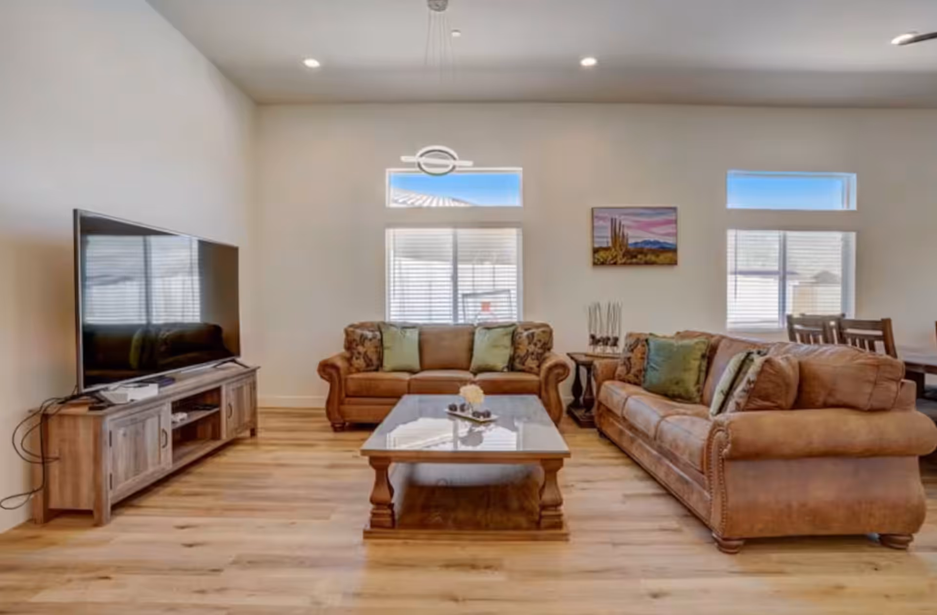 A spacious living room with two brown couches, a coffee table, and a large TV.