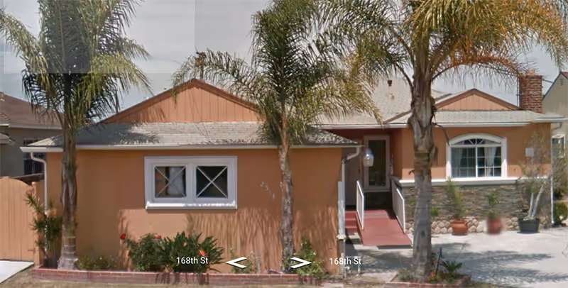 Front exterior of Evergreen Haven Assisted Living, a peach-colored building with palm trees.