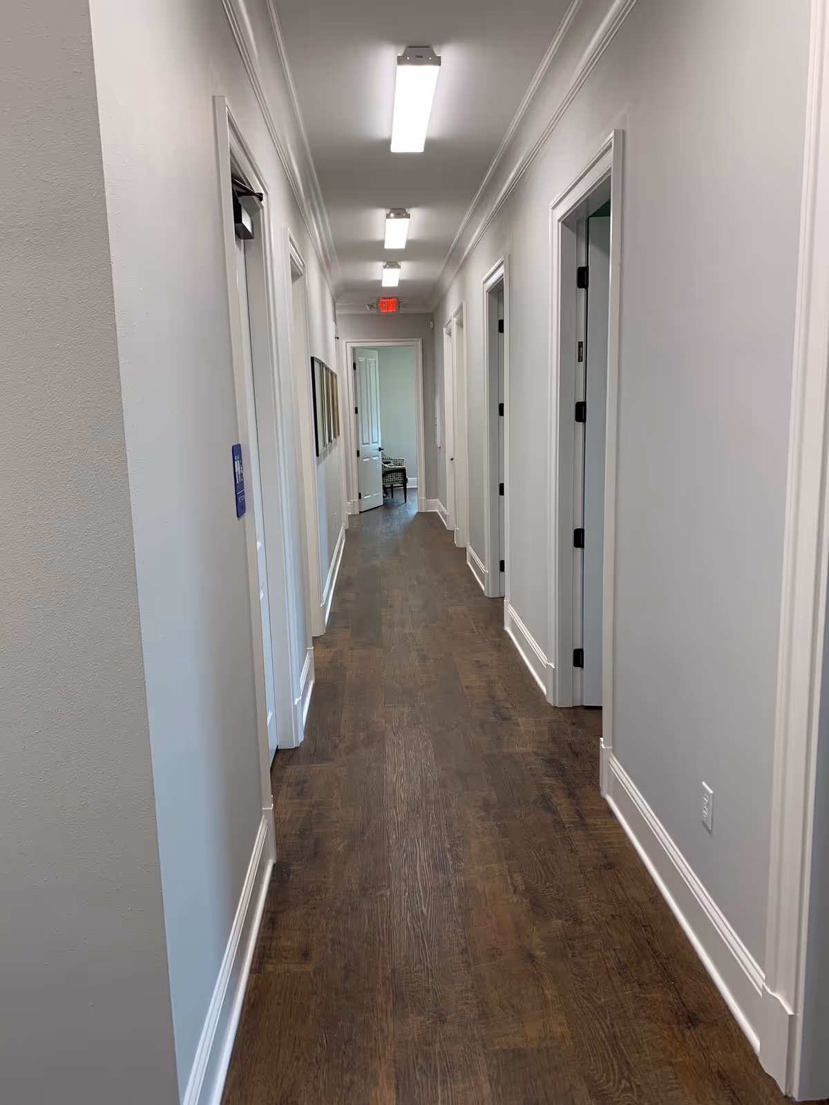 Narrow, well-lit hallway of a senior living facility with multiple doors along both sides.