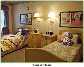 Two twin beds in a cozy resident room with nightstands, lamps, and a plush bear.