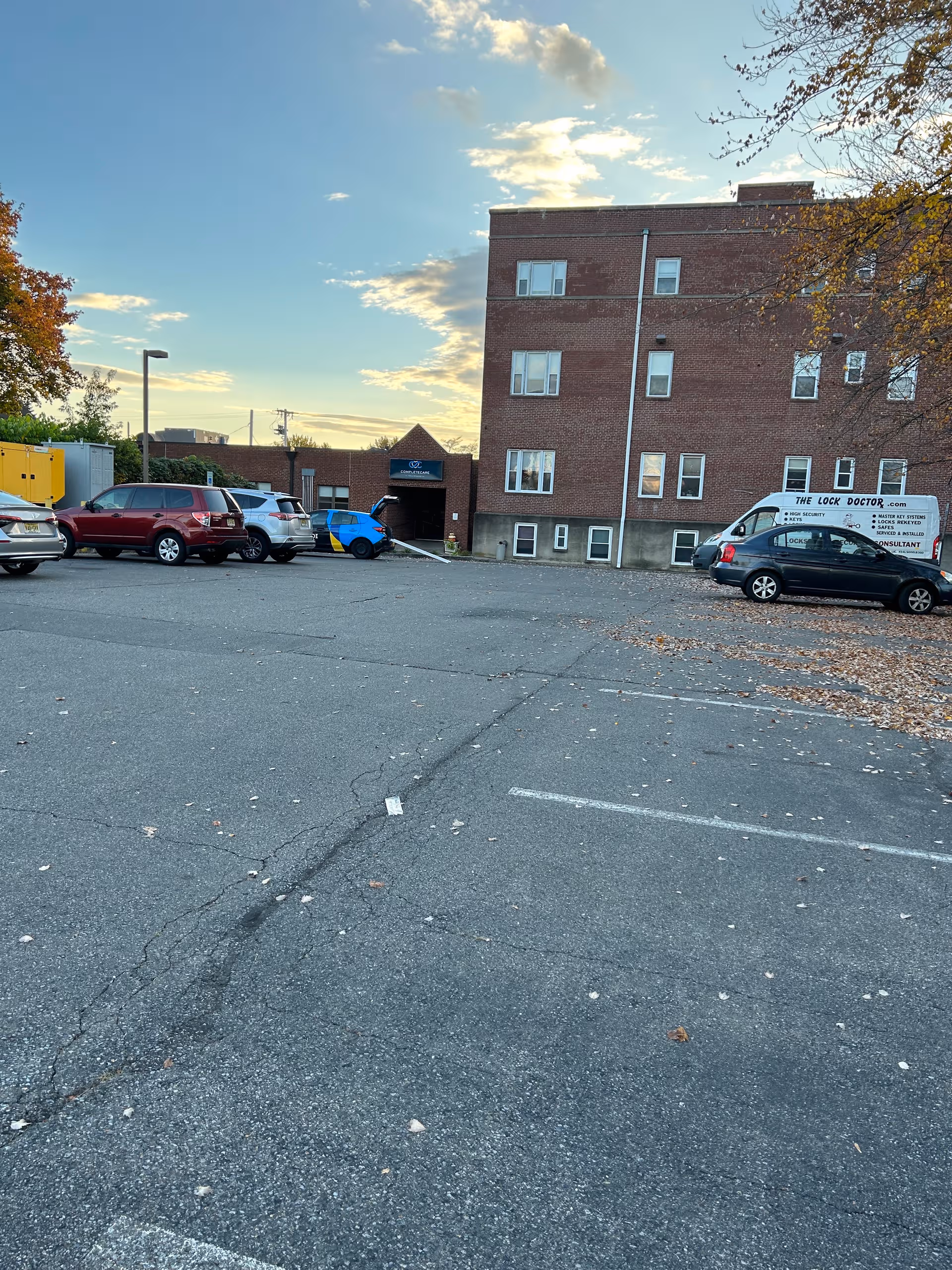 Brick senior living building with parked cars and a paved parking lot.
