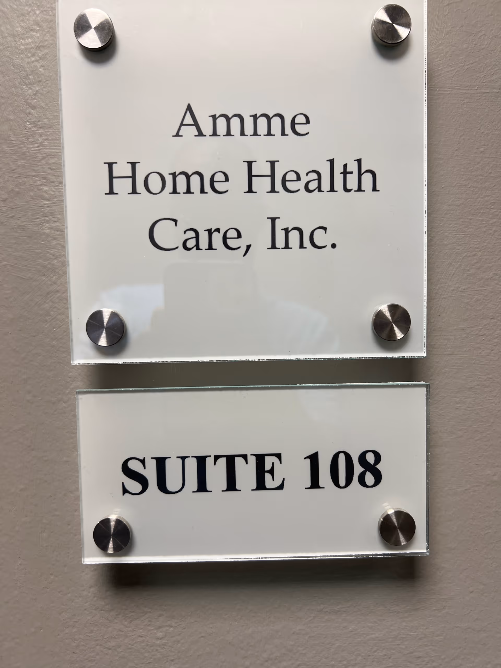 Two glass plaques on a wall read Amme Home Health Care Inc and Suite 108