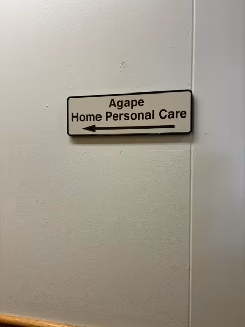 Wall sign pointing left to Agape Home Personal Care in a hallway.