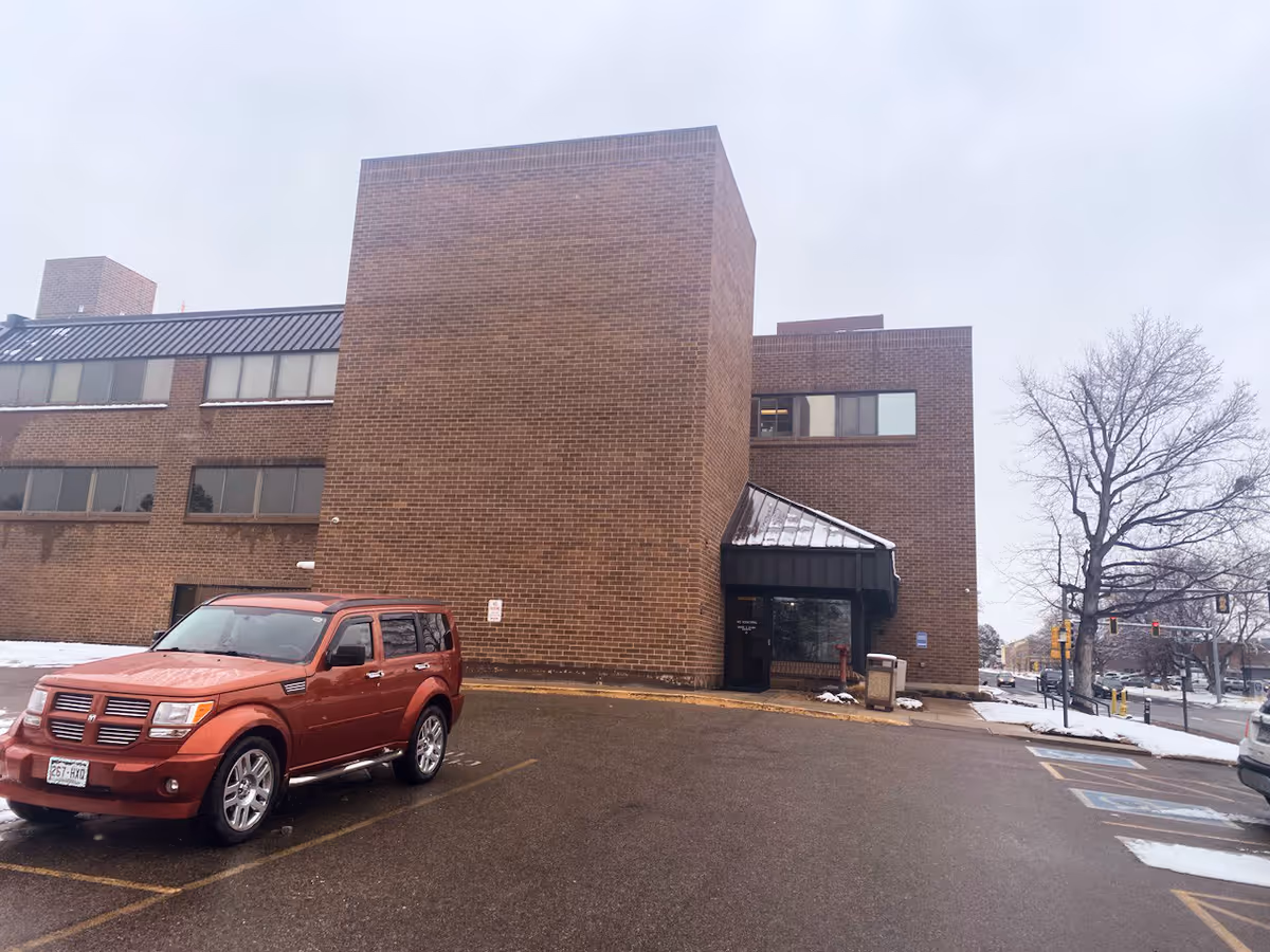 Brick senior living facility exterior with a red SUV in a snow-dusted parking lot.