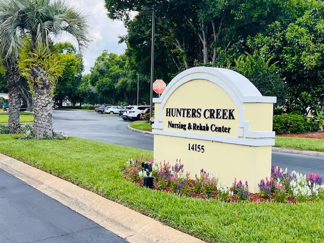 Front entrance sign for Hunter's Creek Nursing and Rehab Center with landscaping.