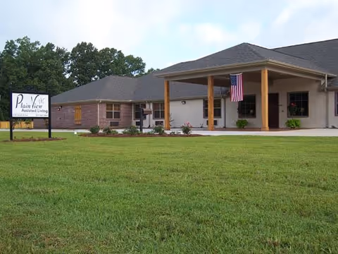 Front view of Plain View Assisted Living building with flag and green lawn
