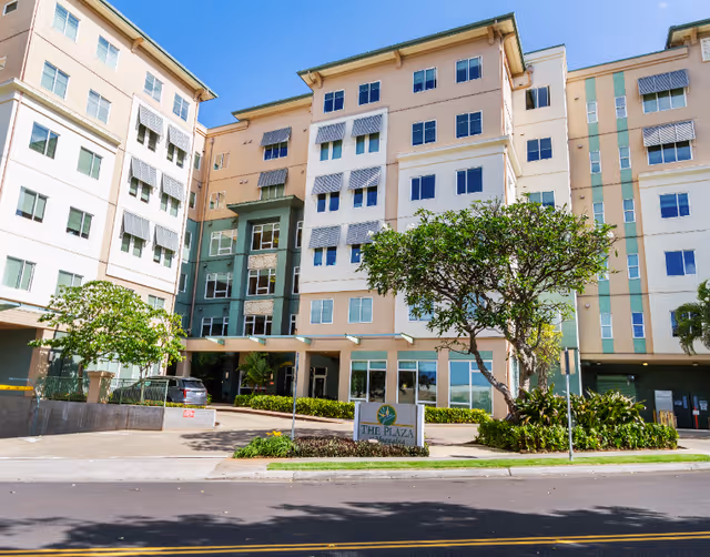 Exterior view of a multi-story senior living building with trees and a front entrance sign.