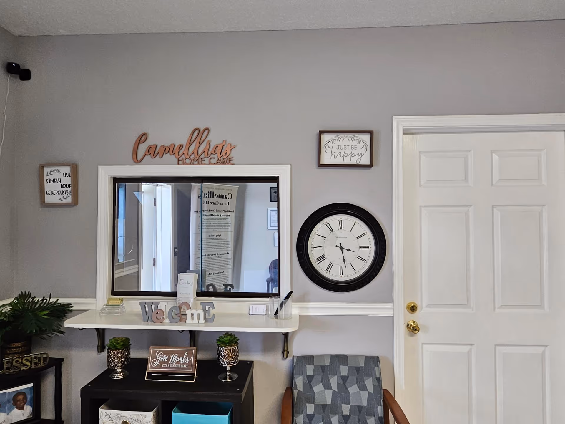 Reception area of Camellia's Home Care with clock, window, welcome sign, and plants.