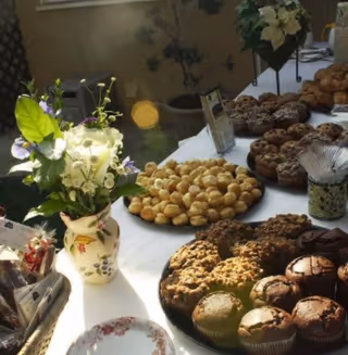 Table of assorted pastries and flowers in a warmly lit dining area.