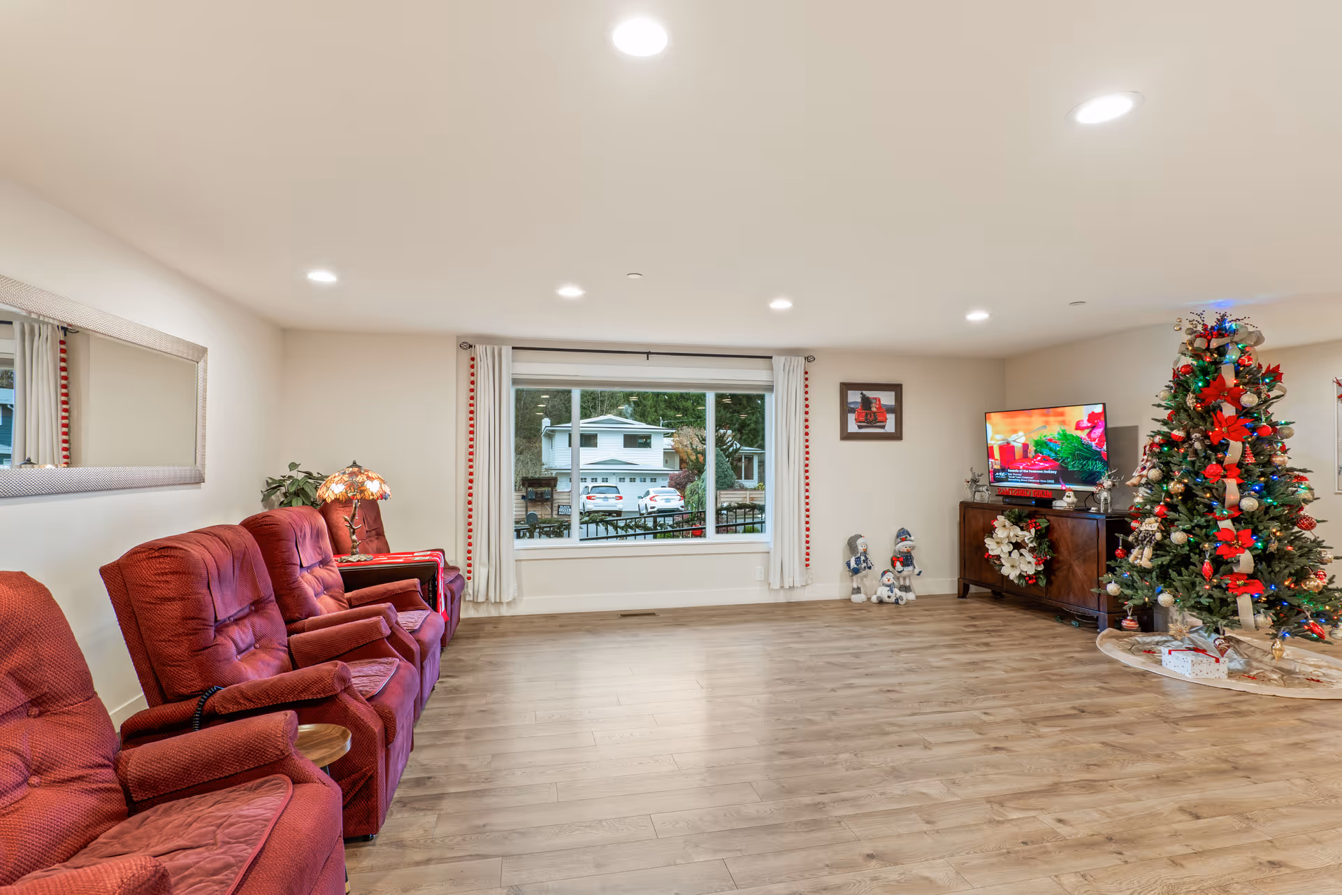 Cozy living room with red recliners, Christmas tree, TV, and large window.
