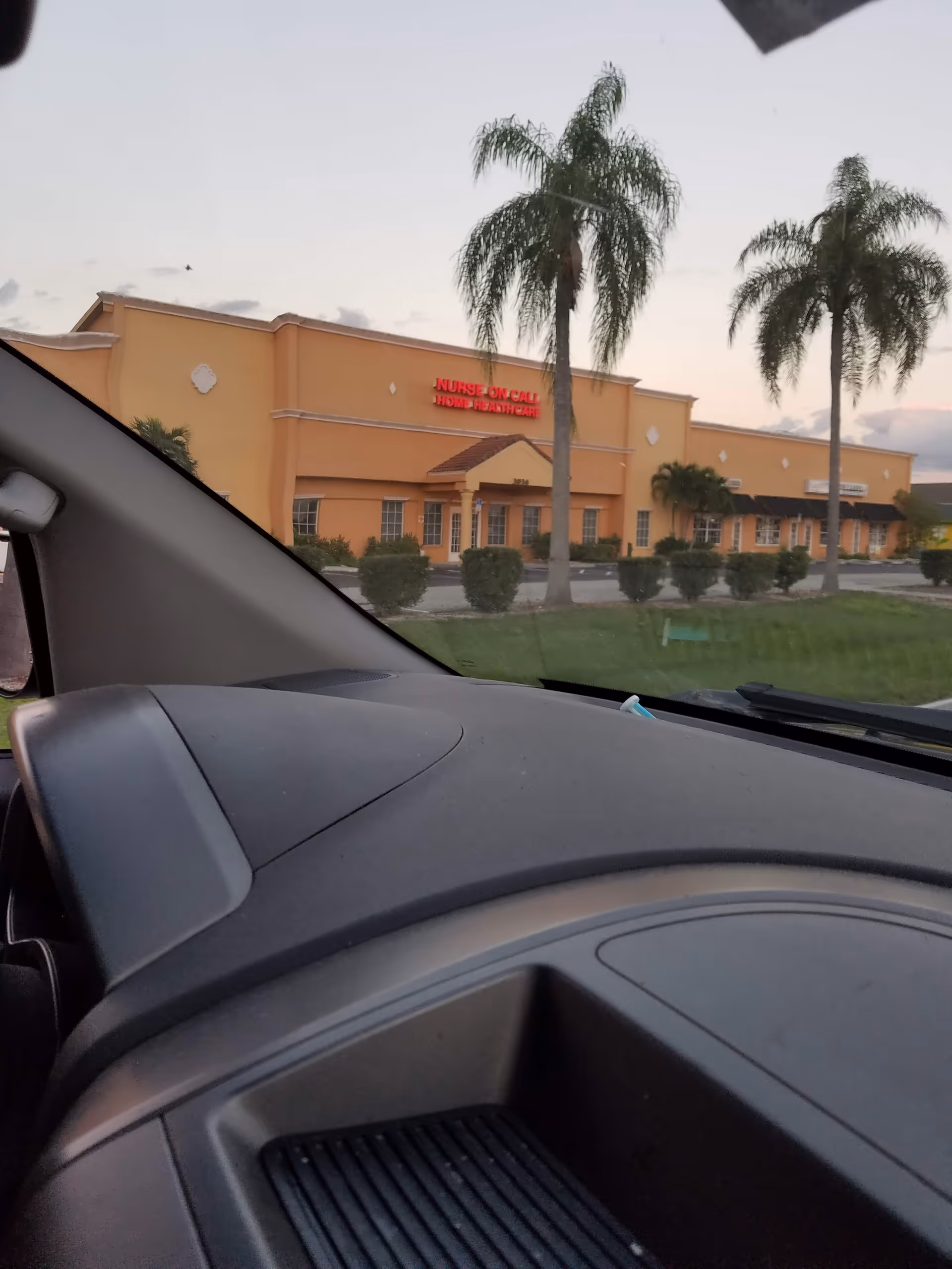 Front exterior of orange healthcare building with palm trees; sign reads Nurse On Call Home Healthcare.