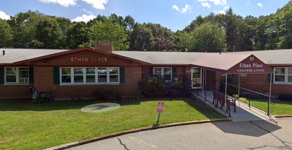 Single-story brick building with Ethan Place signage, an awning, and a ramp at the entrance.