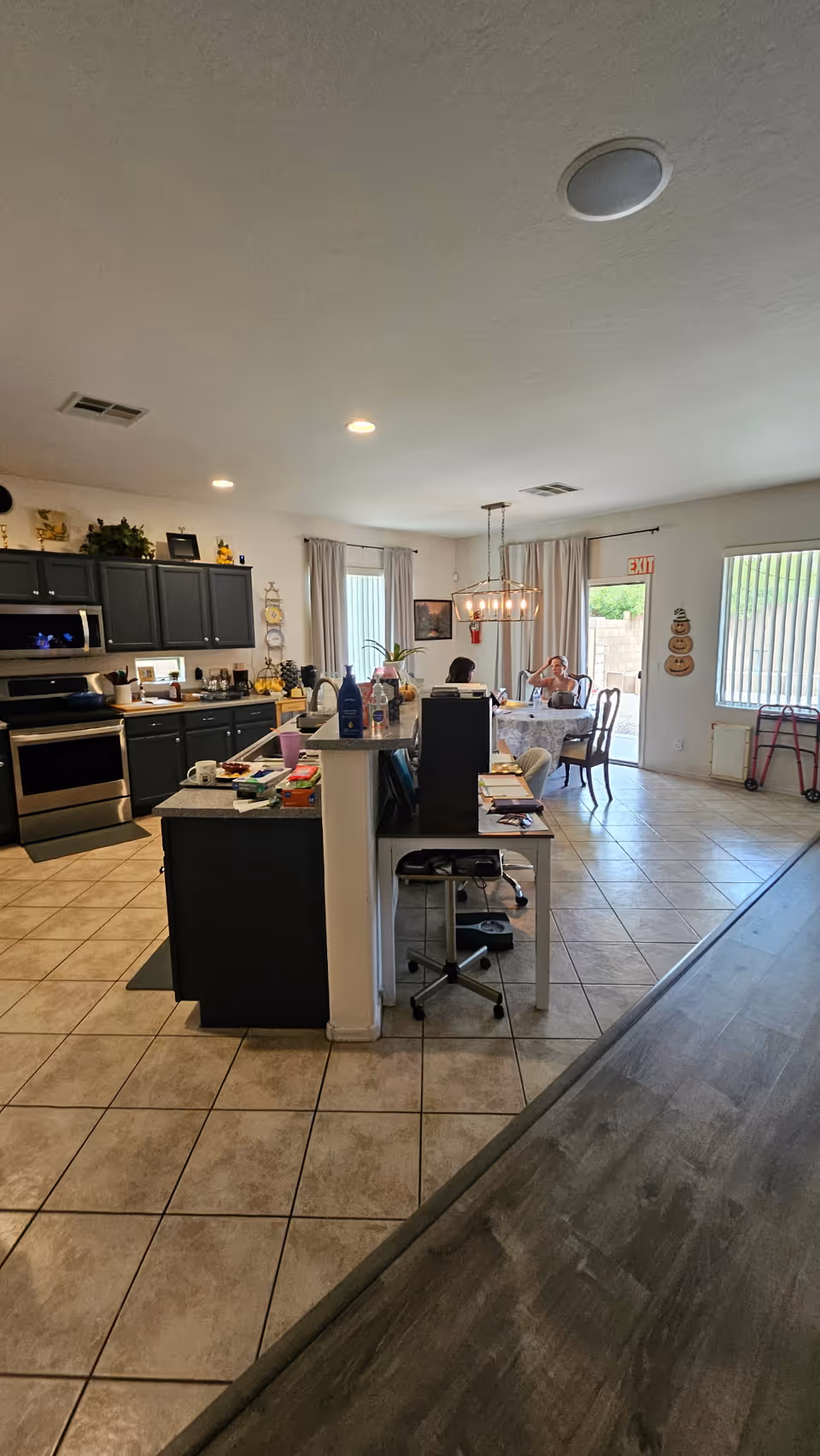 Open-concept kitchen and dining area with cabinets, island, and residents seated at a table.