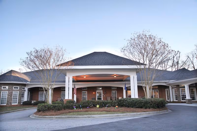 Brick senior living facility entrance with white columns and circular driveway.