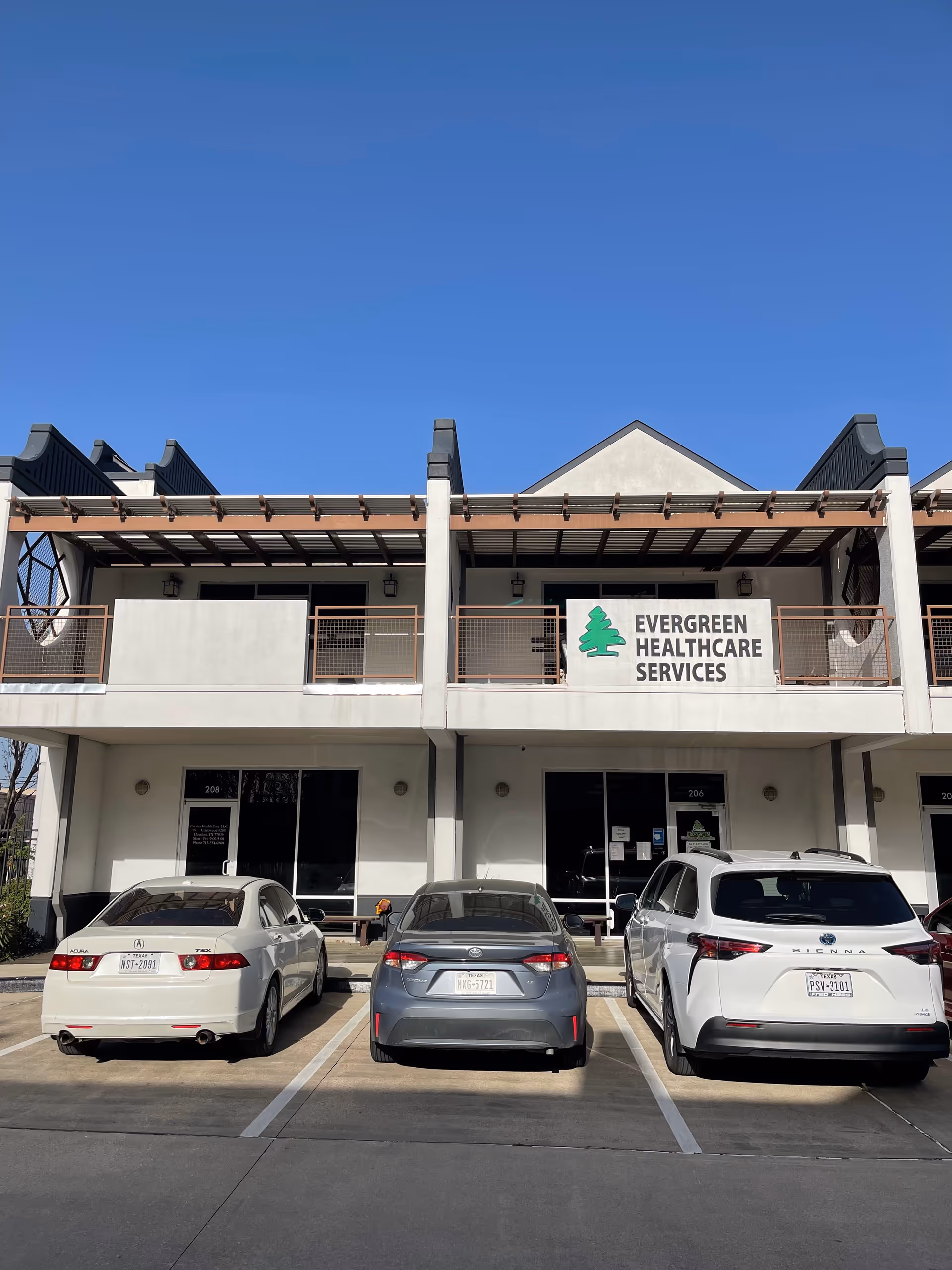 Front view of Evergreen Healthcare Services building with a sign and parked cars.
