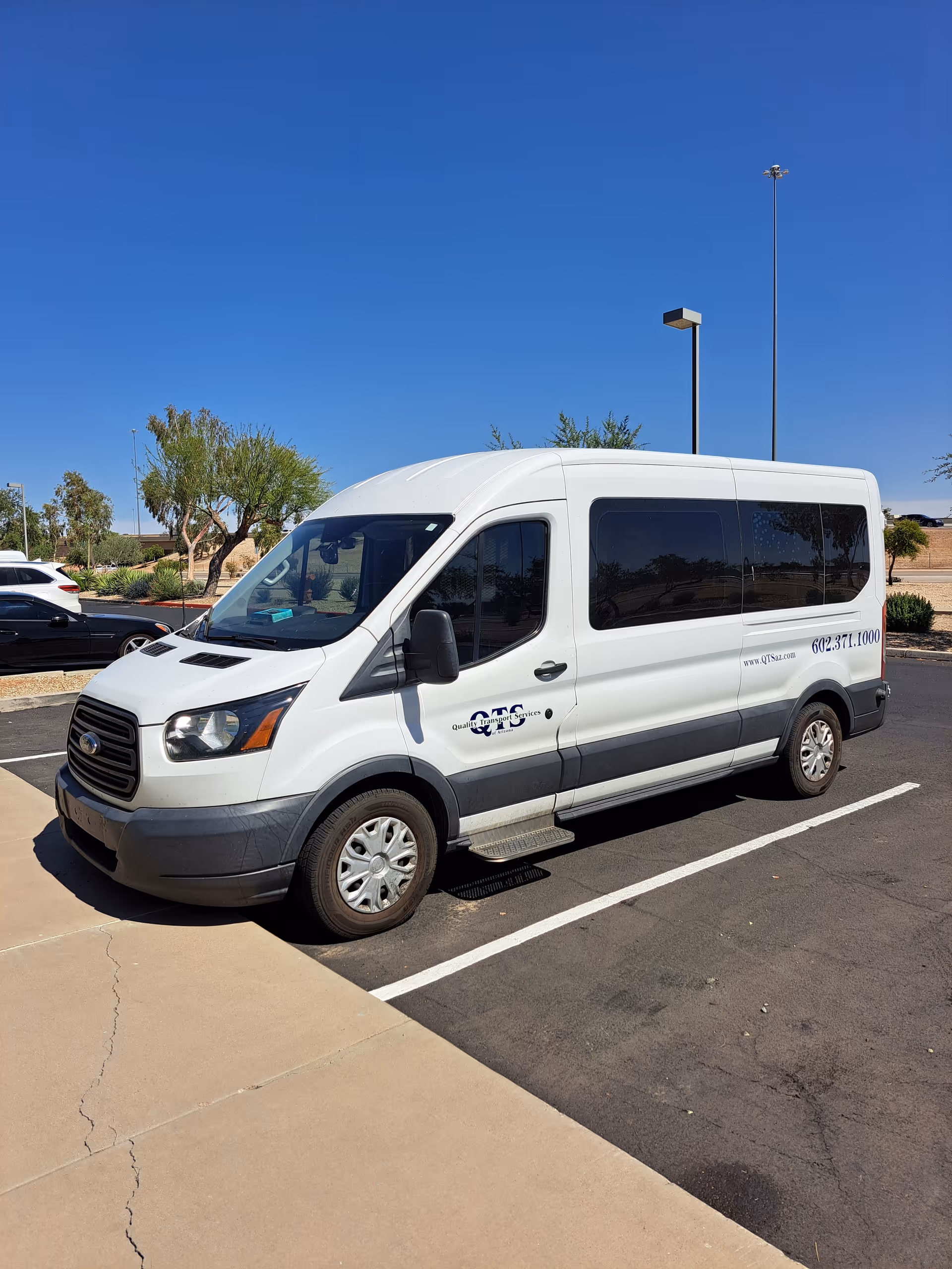White passenger van with dark-tinted windows parked in a sunny lot outside Celestial Care.