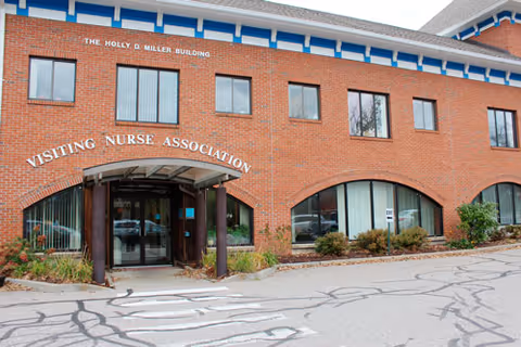 Brick medical building with arched windows and a Visiting Nurse Association sign at entrance.