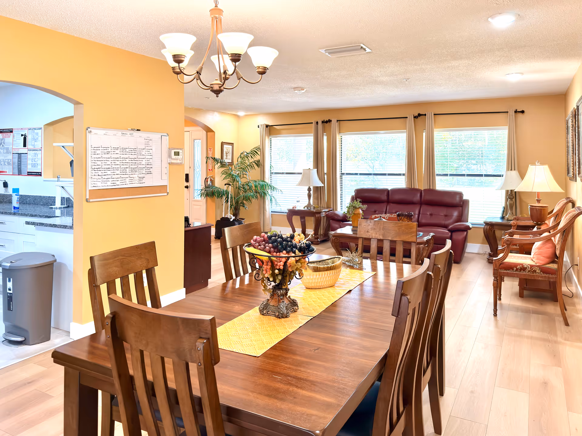 Bright open dining and living area with wooden table and burgundy seating.