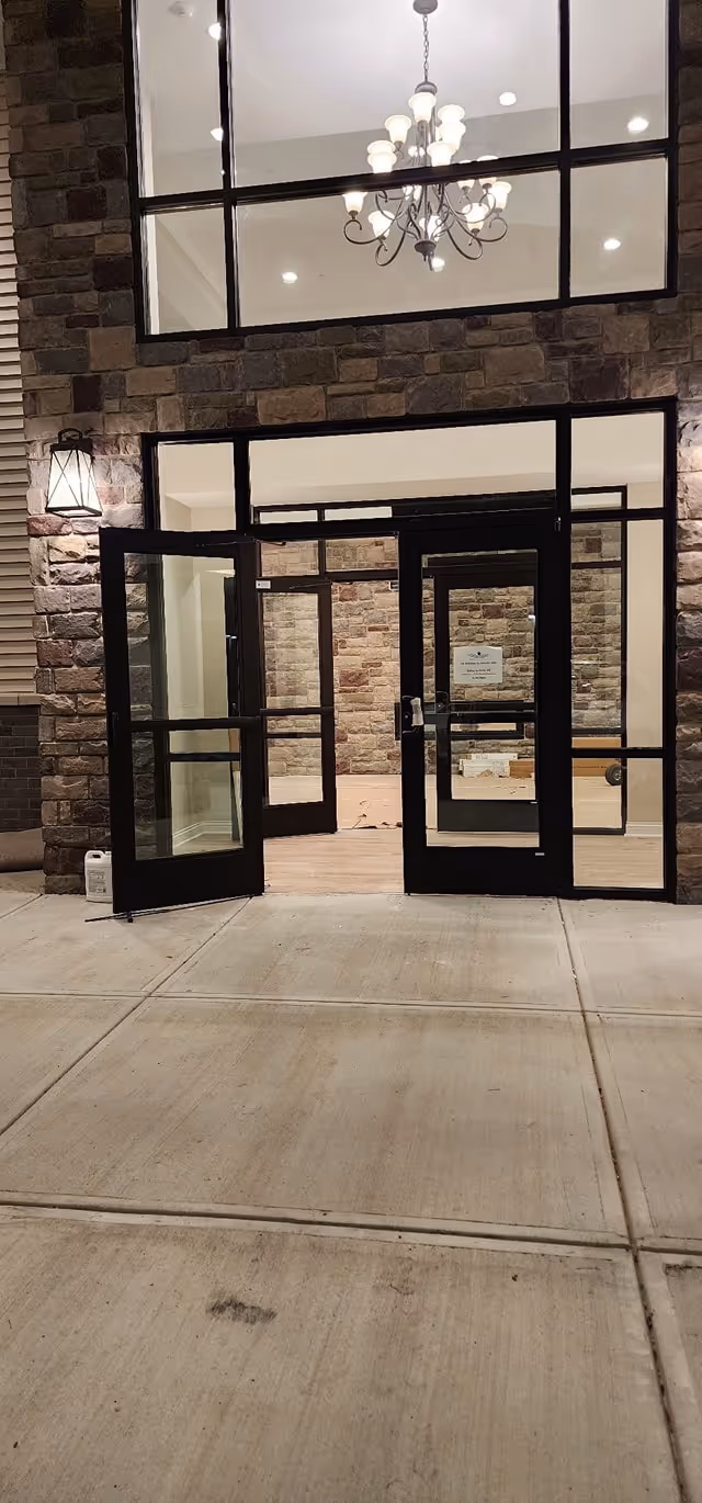 Exterior entrance with glass doors, stone facade, and chandelier in lobby area