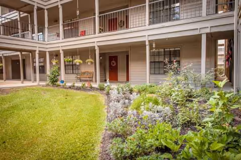 Exterior of a two-story senior living building with balconies and a landscaped courtyard.
