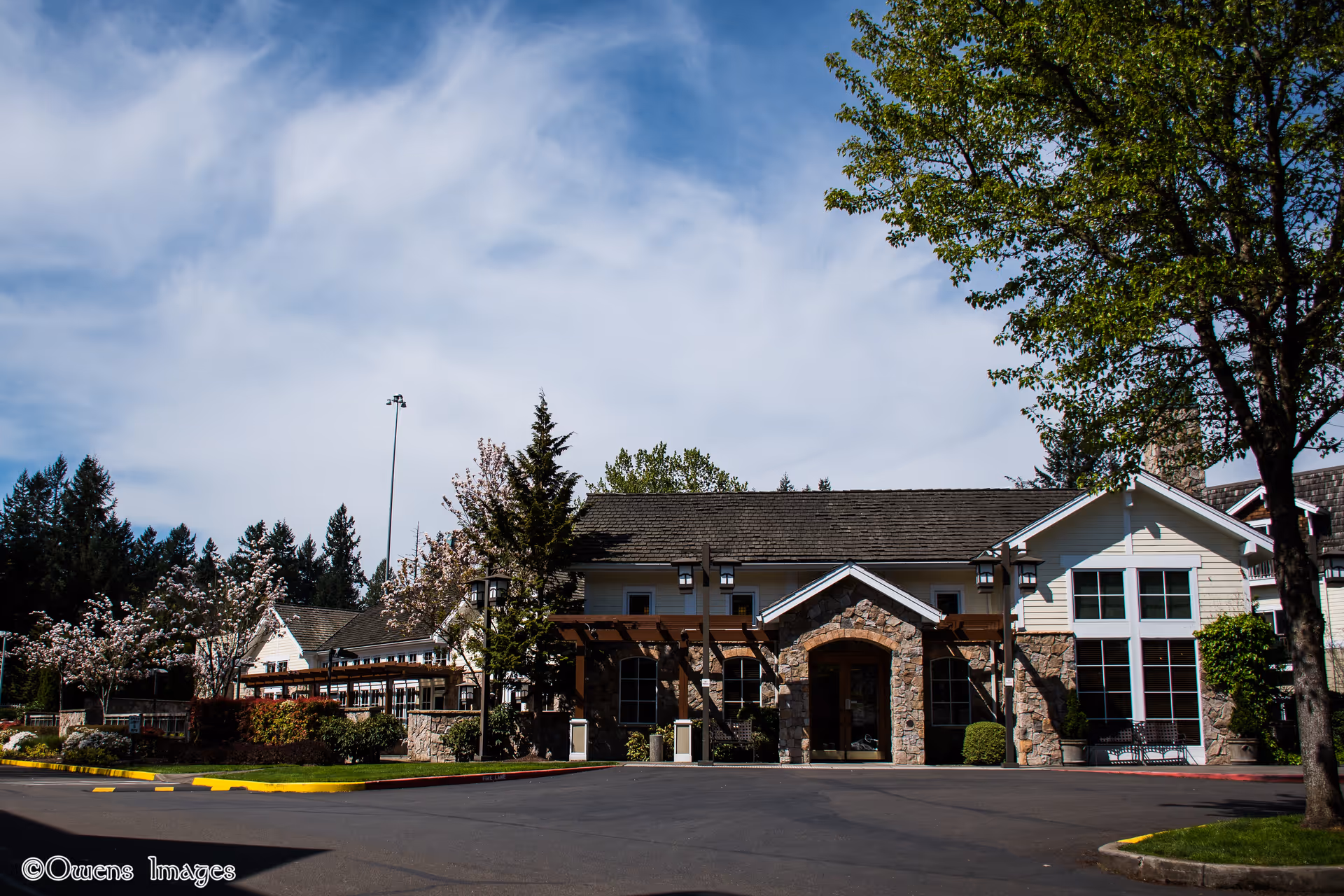 Exterior view of Spring Ridge Court Memory Care building with stone arch entrance and parking.