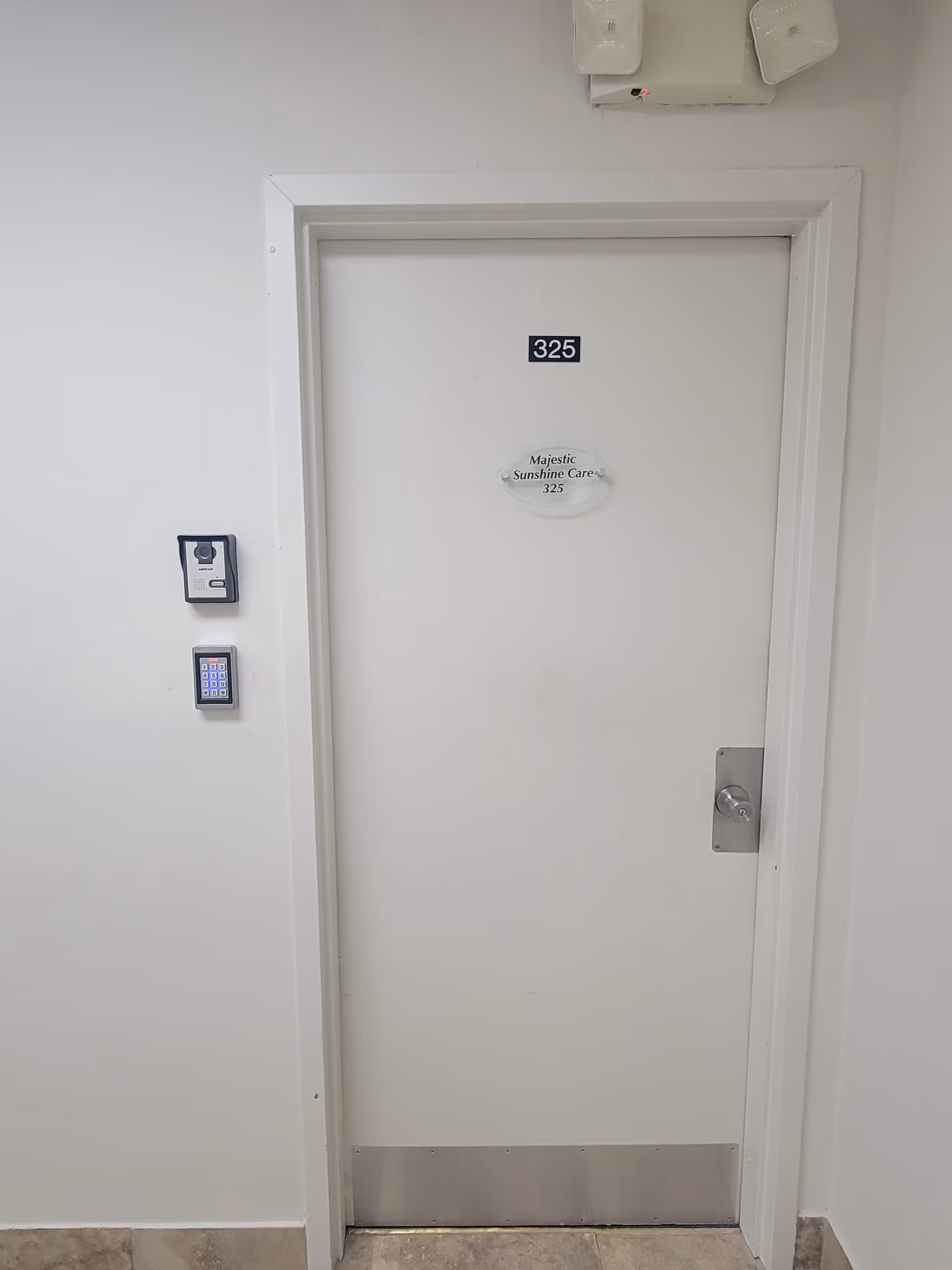 White interior door labeled 325 with Majestic Sunshine Care plaque beside a wall keypad.