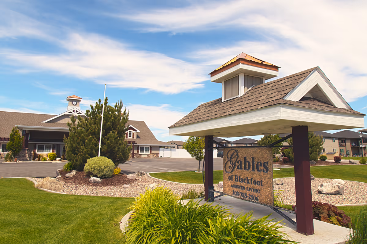 Landscaped front entrance and sign for The Gables Memory Care of Blackfoot with the facility building in the background.