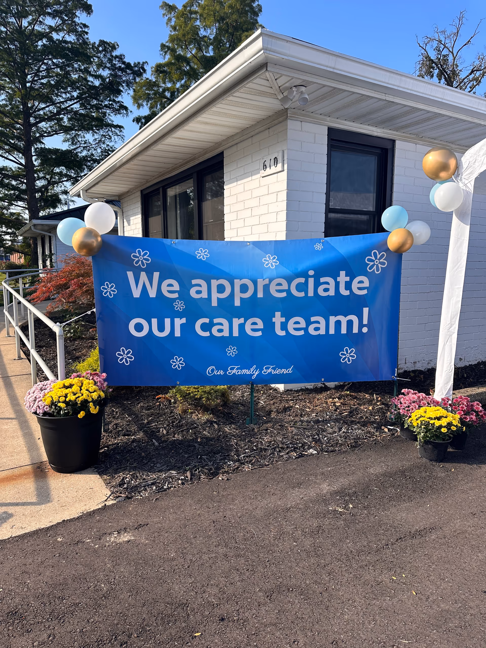 White brick senior facility exterior with a blue banner reading We appreciate our care team.
