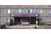 Exterior view of Faith Haven Apartments entrance with maroon awning and glass doors.