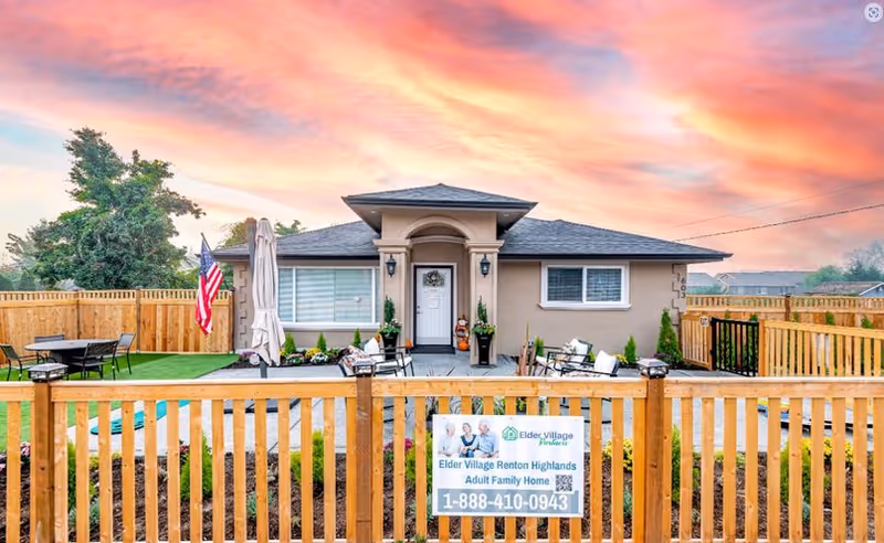 Front view of a single-story home behind a wooden fence with outdoor seating and a sign.