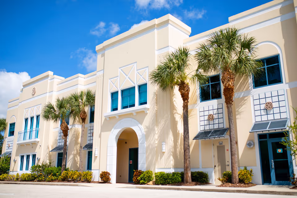 Exterior view of On the Go Therapy senior living facility with palm trees.
