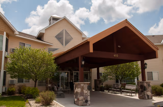 Senior living facility entrance with a covered porte-cochere and stone columns.