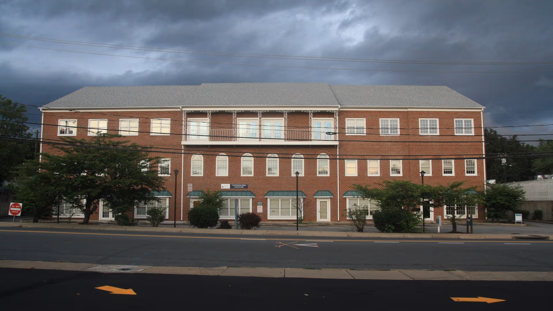 Brick, three-story building on a street with numerous windows and entrances.