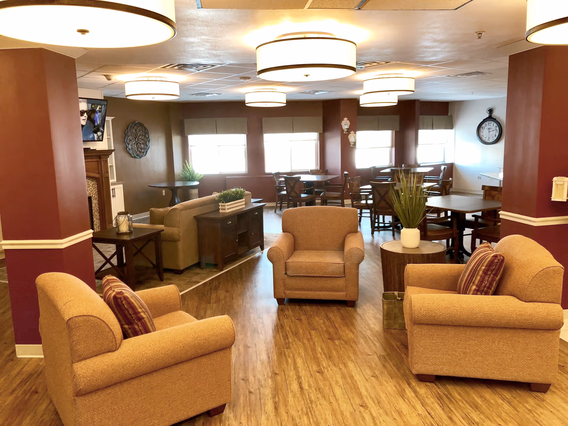 Warm communal lounge with three armchairs around a small table and dining tables in the background.