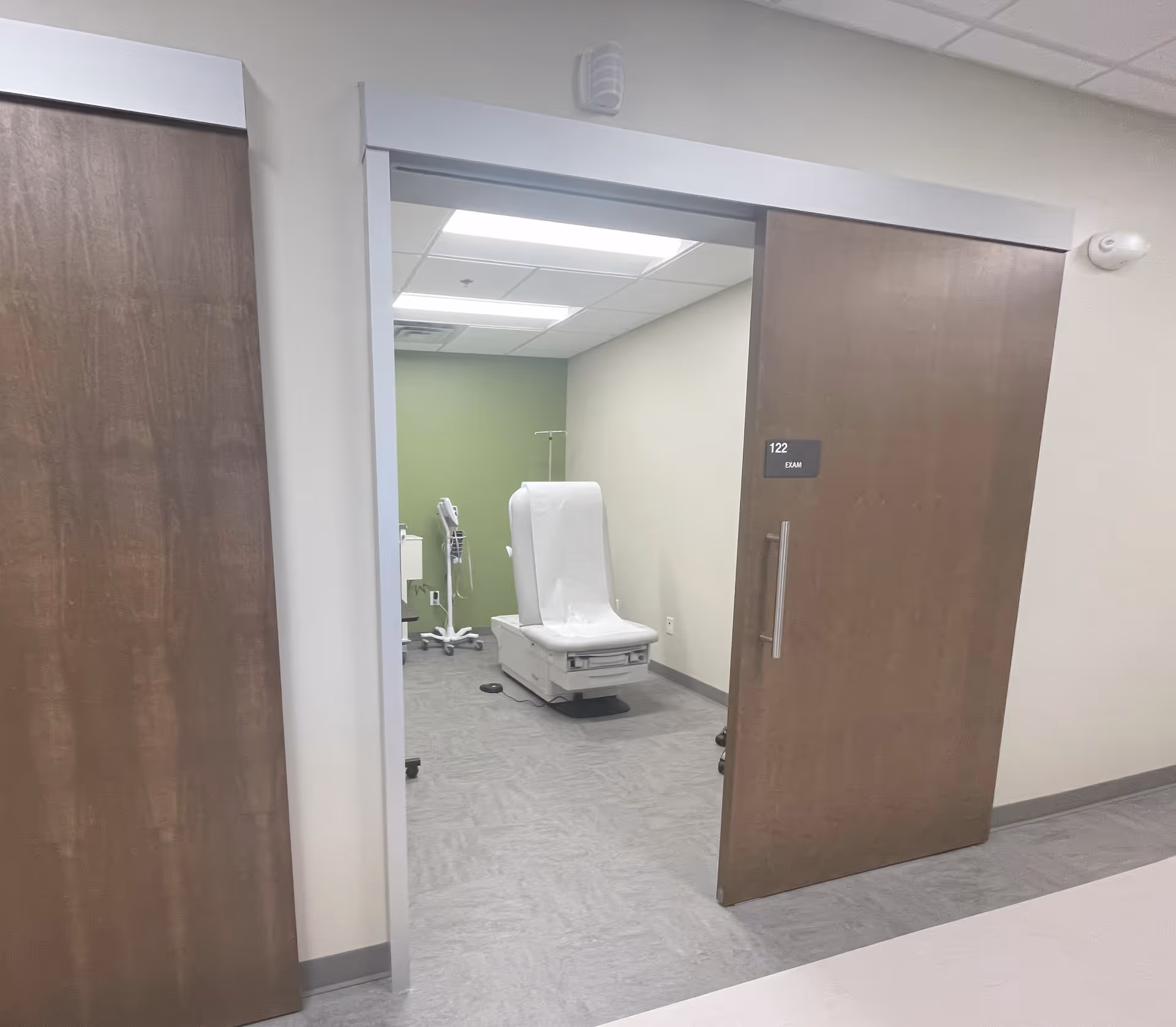 Open doorway reveals an exam room with a white medical chair and equipment.