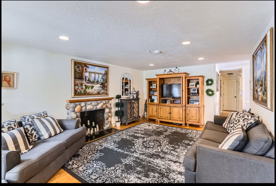 Cozy living room with two gray couches, fireplace, and wooden entertainment center.