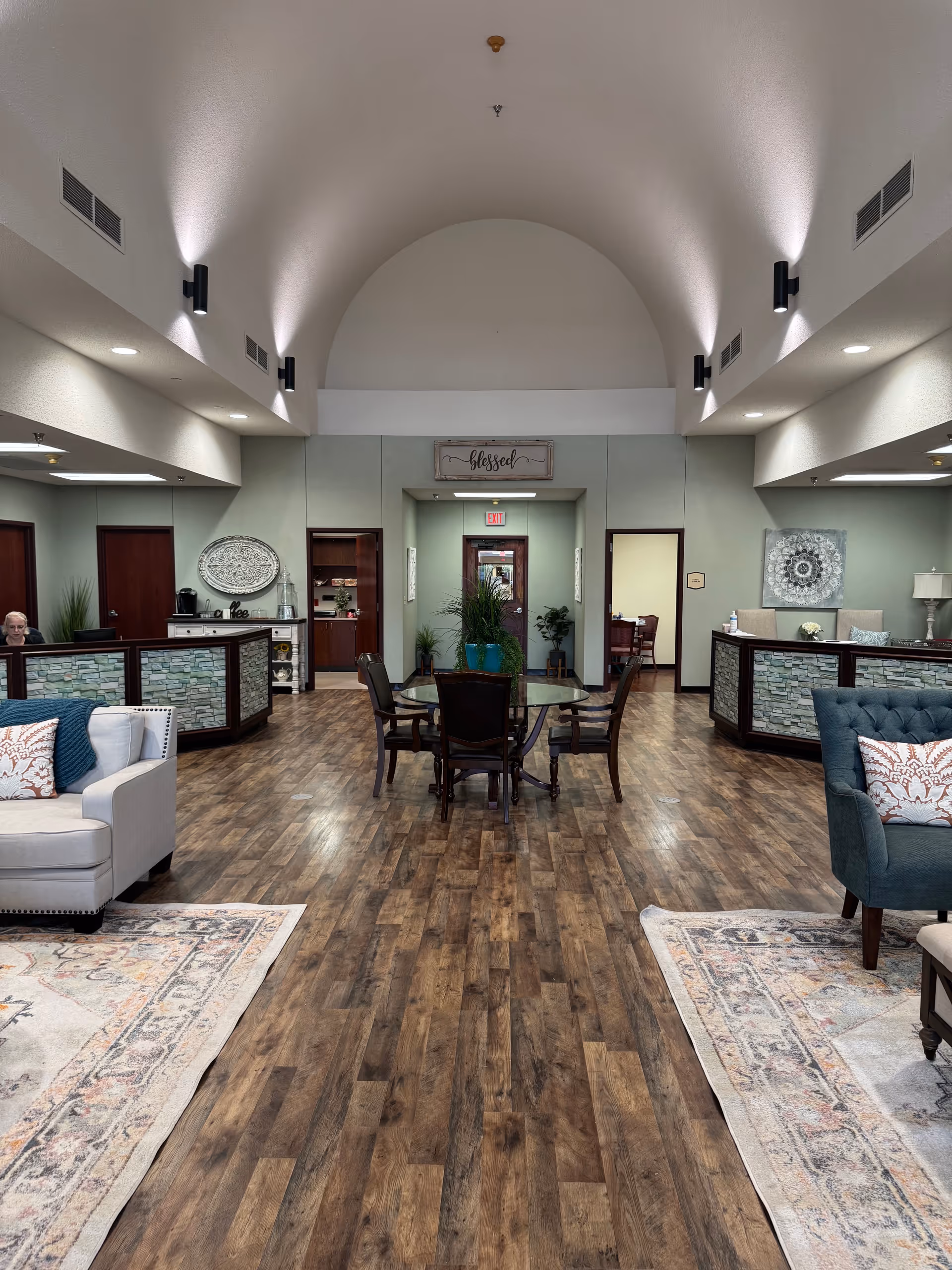 Spacious lobby of Windcrest Health & Rehabilitation with seating, round table, and plants.