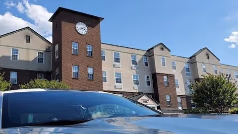 Exterior view of Morningside House of St Charles with clock tower and parked car.